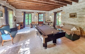 A pool table in a room with stone walls and wooden beams, two sofas, and a billiard cue rack. - 5 bedroom gorgeous home in Sainte-Marthe (Sainte-Marthe)