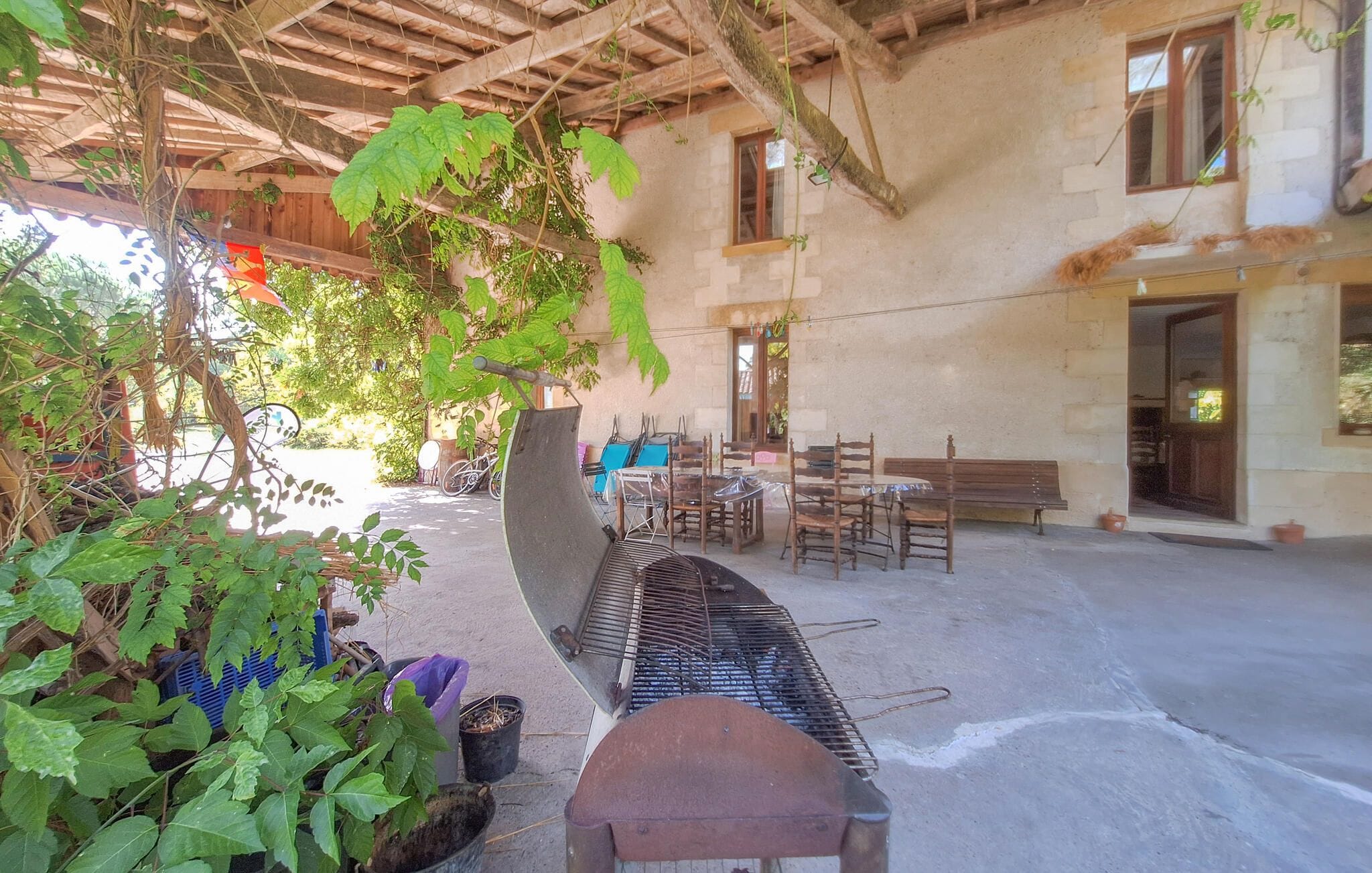 An outdoor seating area with tables and chairs, a bench, and a grill.