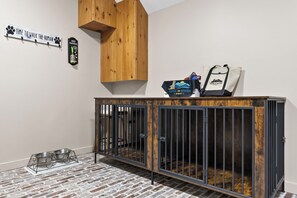 Ein Zimmer mit einem Holzschrank, einer Metall-Hundeschüssel auf dem Boden und einem an der Wand befestigten Kleiderhaken.
