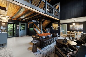 Ein geräumiger Wohnbereich mit einer Ledersofa, einem runden Couchtisch und einem Esstisch. Eine Treppe führt zu einer oberen Ebene.