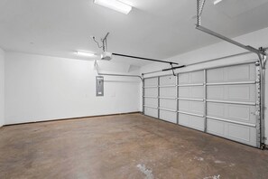 Uma garagem com piso de concreto, porta branca e ventilador de teto.
