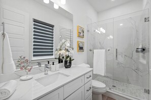 Ein modernes Badezimmer mit einem weißen Waschtisch, einer Duschkabine aus Glas und einer Toilette.