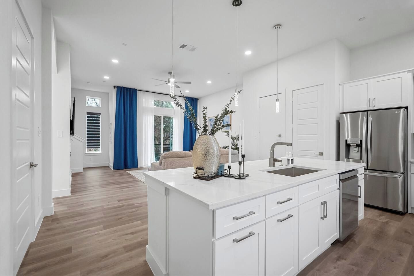 A modern kitchen with white cabinetry, a stainless steel refrigerator, and a central island with a sink.
