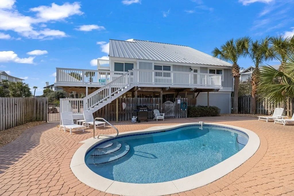 Uma casa de dois andares com piscina, área de estar externa e varanda coberta.