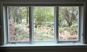 A window with a view of a forested area with rocks and trees. - Red Rock Ridge- 2 Bedroom Suite (Wheat Ridge)