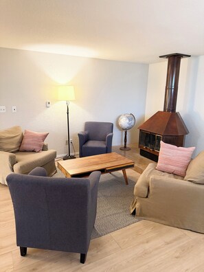 A living room with a sofa, armchair, coffee table, lamp, globe, and a wood-burning stove. - Red Rock Ridge- 2 Bedroom Suite (Wheat Ridge)
