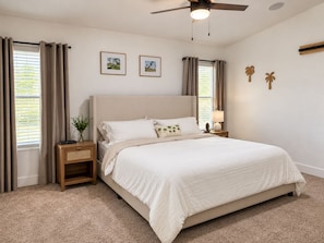 A bedroom with a bed, nightstands, a ceiling fan, and two framed pictures on the wall. - 1 mile to Spring Training - Backyard Oasis - Pool Hot Tub -4BR Single Level Home (Goodyear)