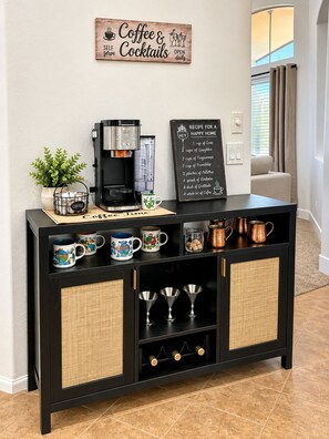 Ein Kaffee-Bereich mit Kaffeemaschine, Tassen und einem Schild, das täglichen Betrieb anzeigt.