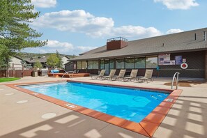 A rectangular swimming pool with a lifeguard chair and lounge chairs, surrounded by a concrete deck. - Spacious Prospector 3BR | Sleeps 8 | Pool & Hot Tub (Park City)