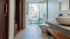 Une salle de bain moderne dotée d’un grand lavabo, de toilettes et d’un espace douche.