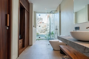 Un baño moderno con un lavamanos grande, inodoro y zona de ducha.