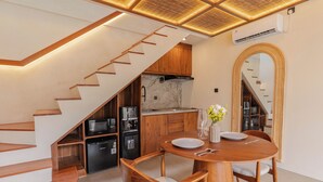 Une cuisine moderne dotée d’appareils électroménagers intégrés, un coin repas avec des meubles en bois et un escalier menant à un autre niveau.