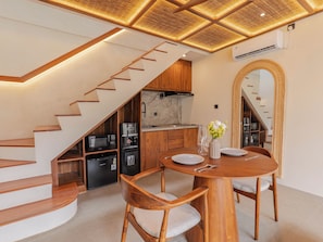 Una cocina moderna con electrodomésticos integrados, un comedor con mobiliario de madera y una escalera que sube a otro nivel.