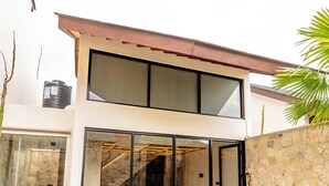 Une maison moderne à deux étages, dotée d’une piscine, de grandes portes vitrées et d’un mur en pierre.