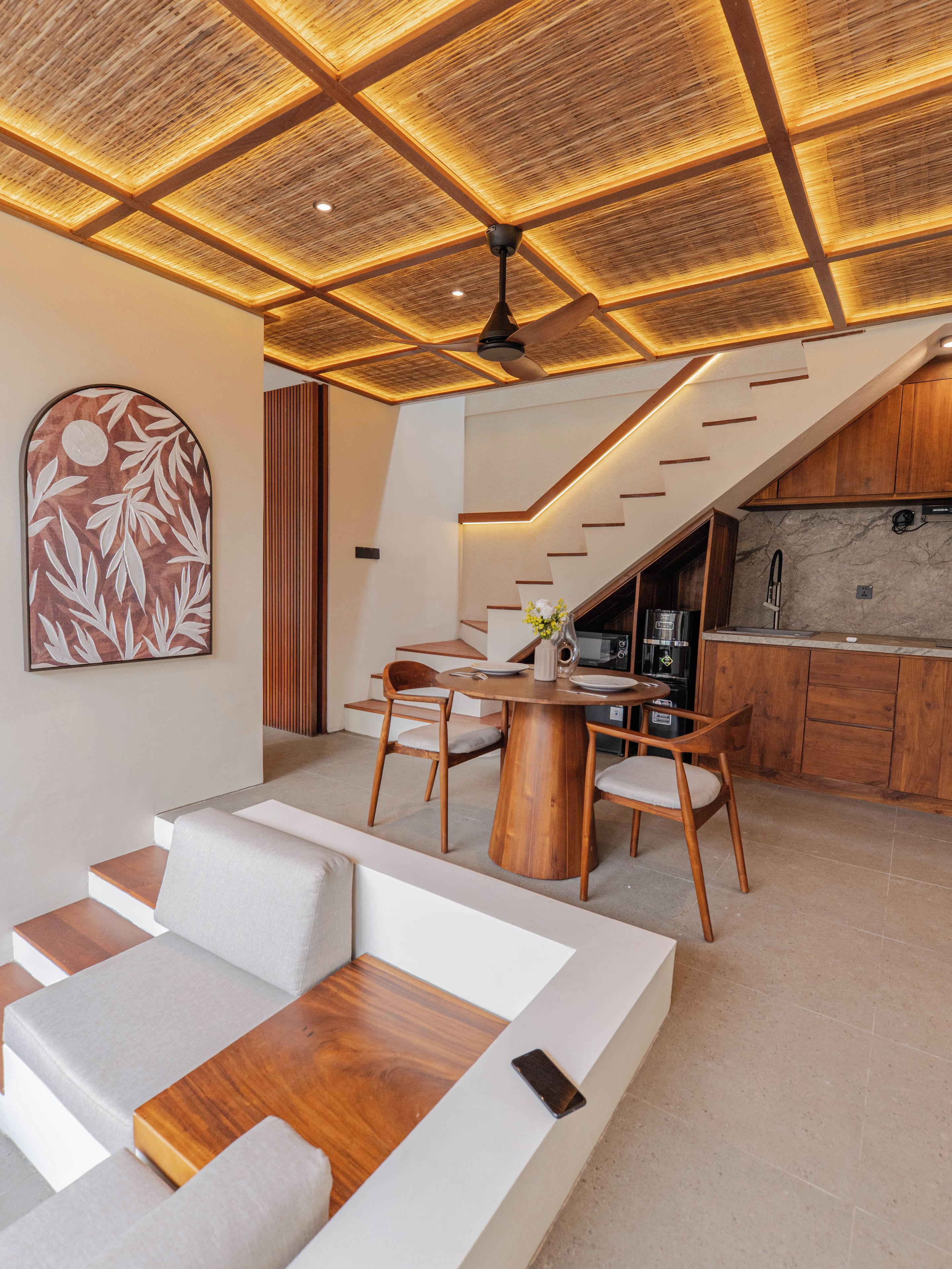 A modern interior with a dining area, kitchen, and staircase.