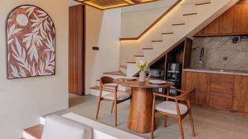 A modern interior with a dining area, kitchen, and staircase.