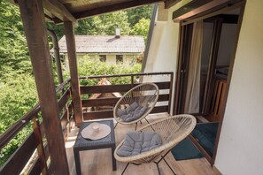 Ein Balkon mit zwei Korbstühlen, einem Tisch und Blick auf ein Haus.