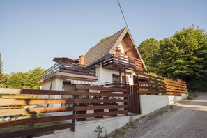 Une maison moderne avec un toit en pente, une clôture en bois et une allée gravillonnée.