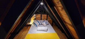 Acogedor dormitorio en el ático con cama, almohadas y mesita de noche.