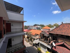 Un immeuble à plusieurs étages, doté de balcons et offrant une vue sur une ville aux maisons traditionnelles.