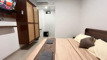 Habitación de hotel con cama, almohadas, televisor, armario y aire acondicionado.