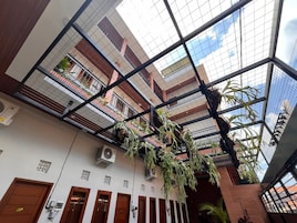 Um átrio de vários níveis com teto de vidro, varandas múltiplas e plantas pendentes.