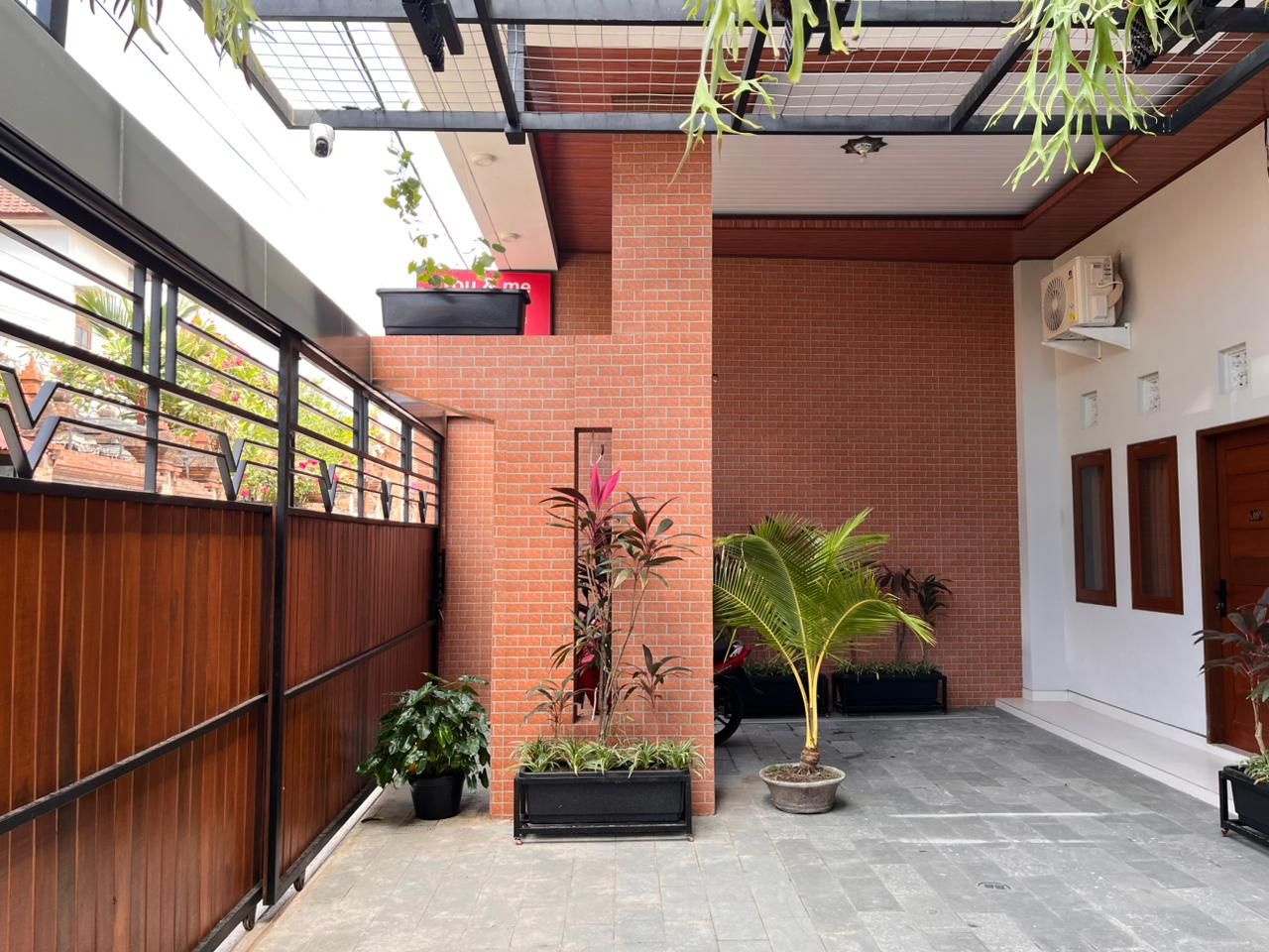 Un patio con muro de ladrillo, valla de madera y plantas en macetas.
