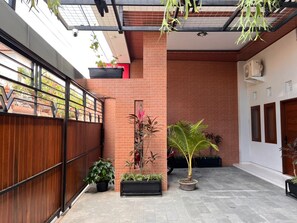 Une cour avec un mur en briques, une clôture en bois et des plantes en pot.