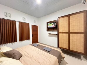 Une chambre à coucher avec un lit, des rideaux, un téléviseur et une porte coulissante.