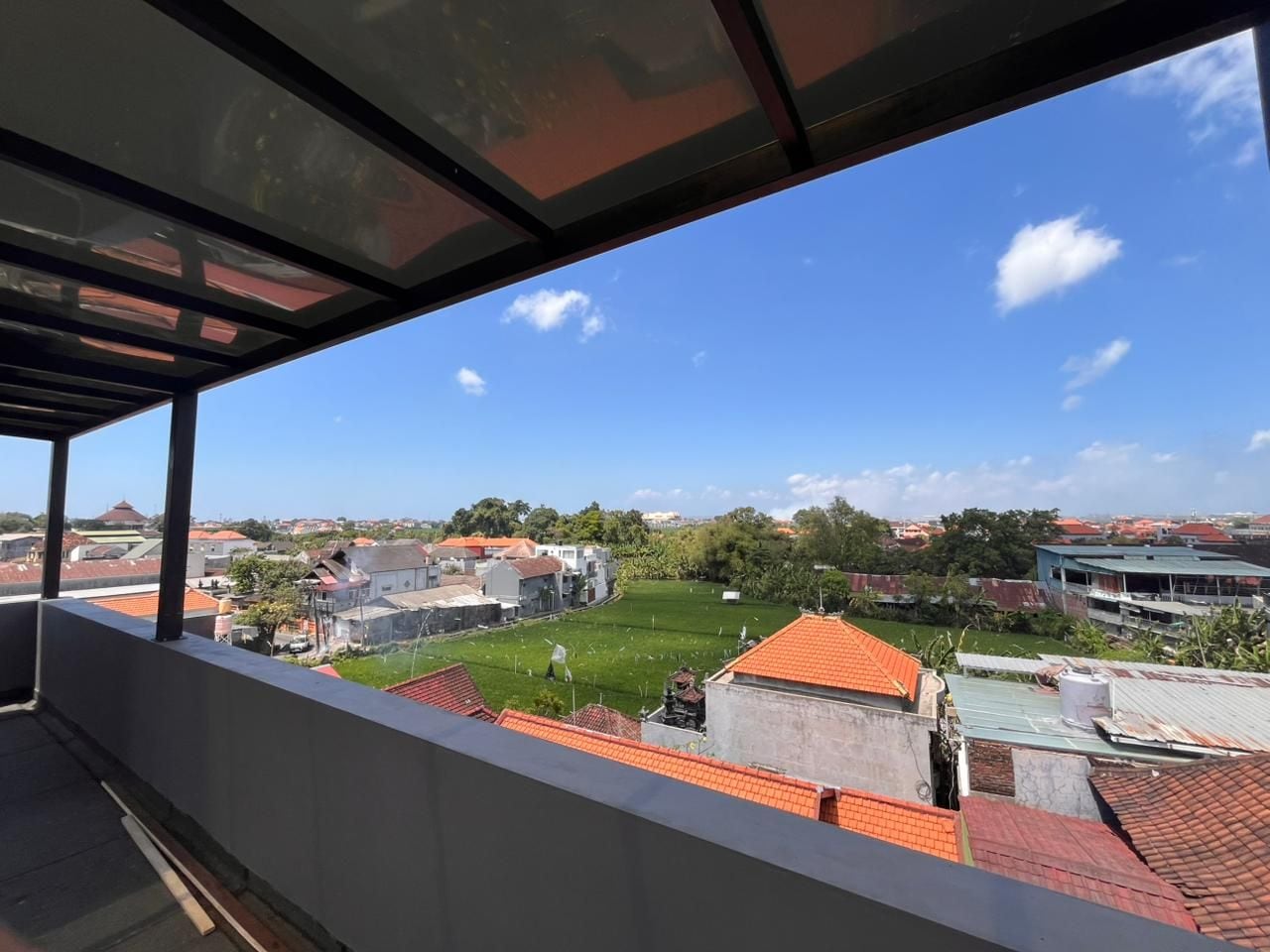 Un balcón con vistas a una zona residencial, que incluye casas y un área verde.