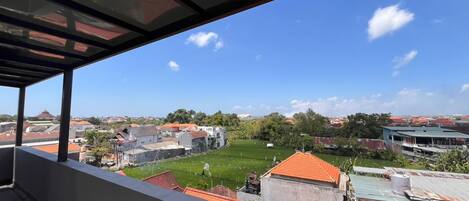 Un balcón con vistas a una zona residencial, que incluye casas y un área verde.