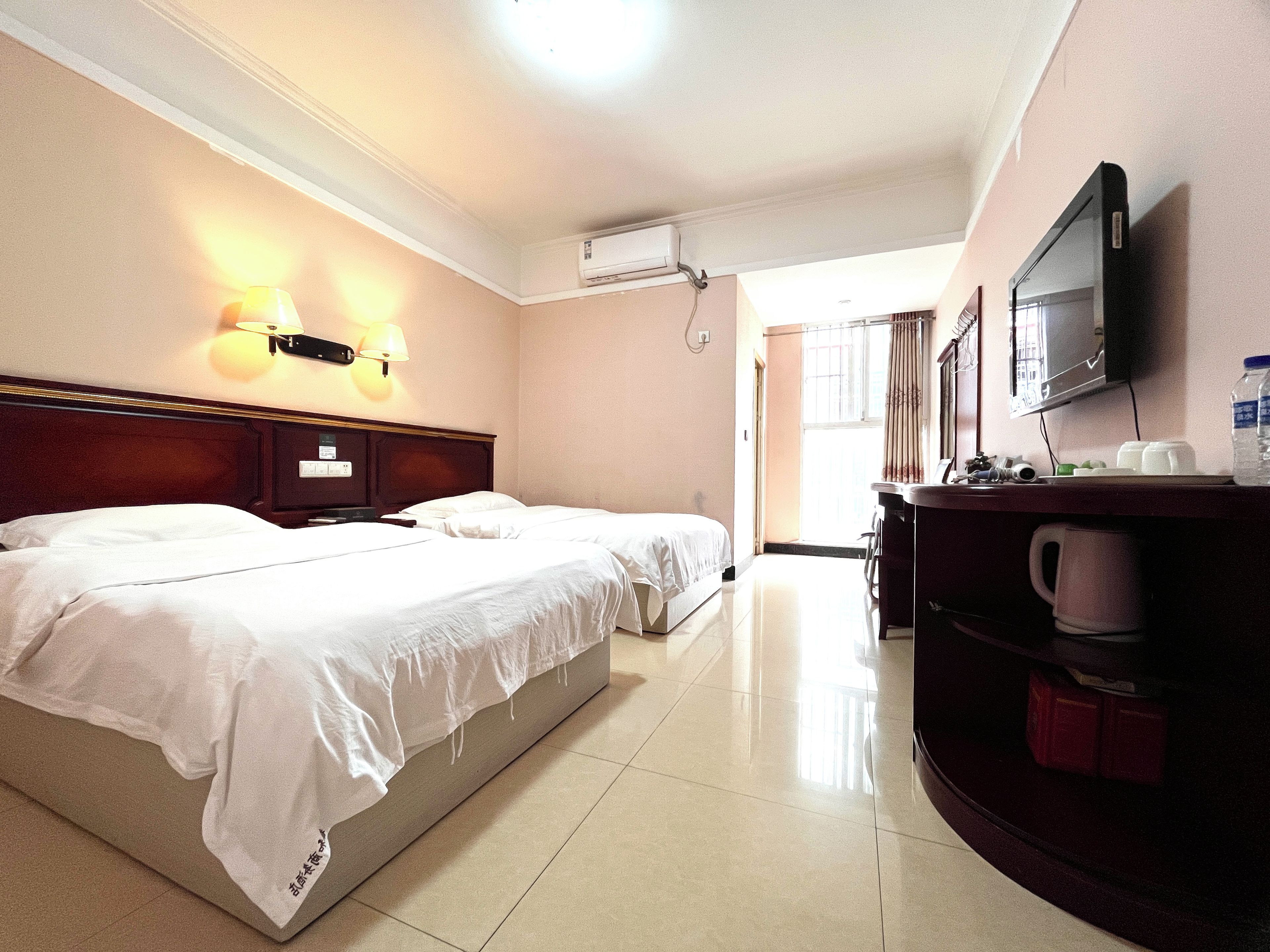 A hotel room with two beds, a flat-screen TV, a desk with a chair, and a coffee maker.