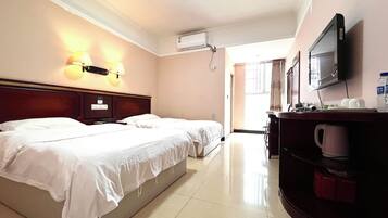 A hotel room with two beds, a flat-screen TV, a desk with a chair, and a coffee maker.
