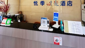 Una recepción de hotel con un letrero que indica una clasificación de 2 estrellas, una computadora, un teléfono y un código QR para el registro.