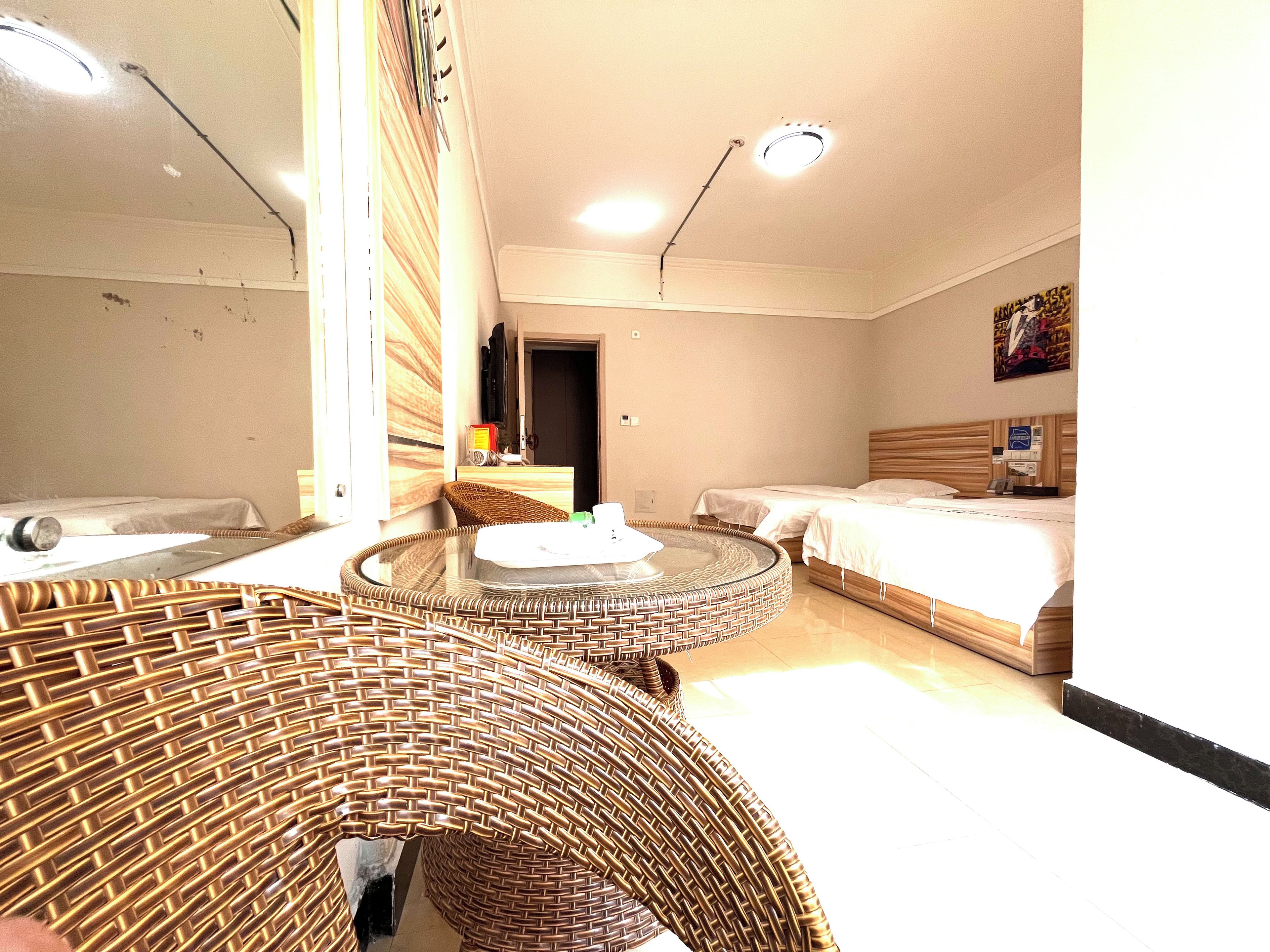 A hotel room with a round wicker sofa, a bed with a wooden headboard, and a small round table.