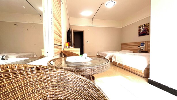 Habitación de hotel con un sofá redondo de mimbre, una cama con cabecera de madera y una pequeña mesa redonda.
