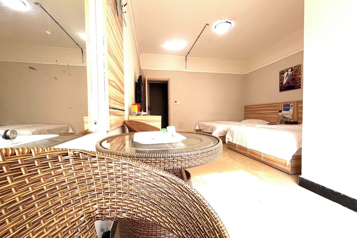 Habitación de hotel con un sofá redondo de mimbre, una cama con cabecera de madera y una pequeña mesa redonda.