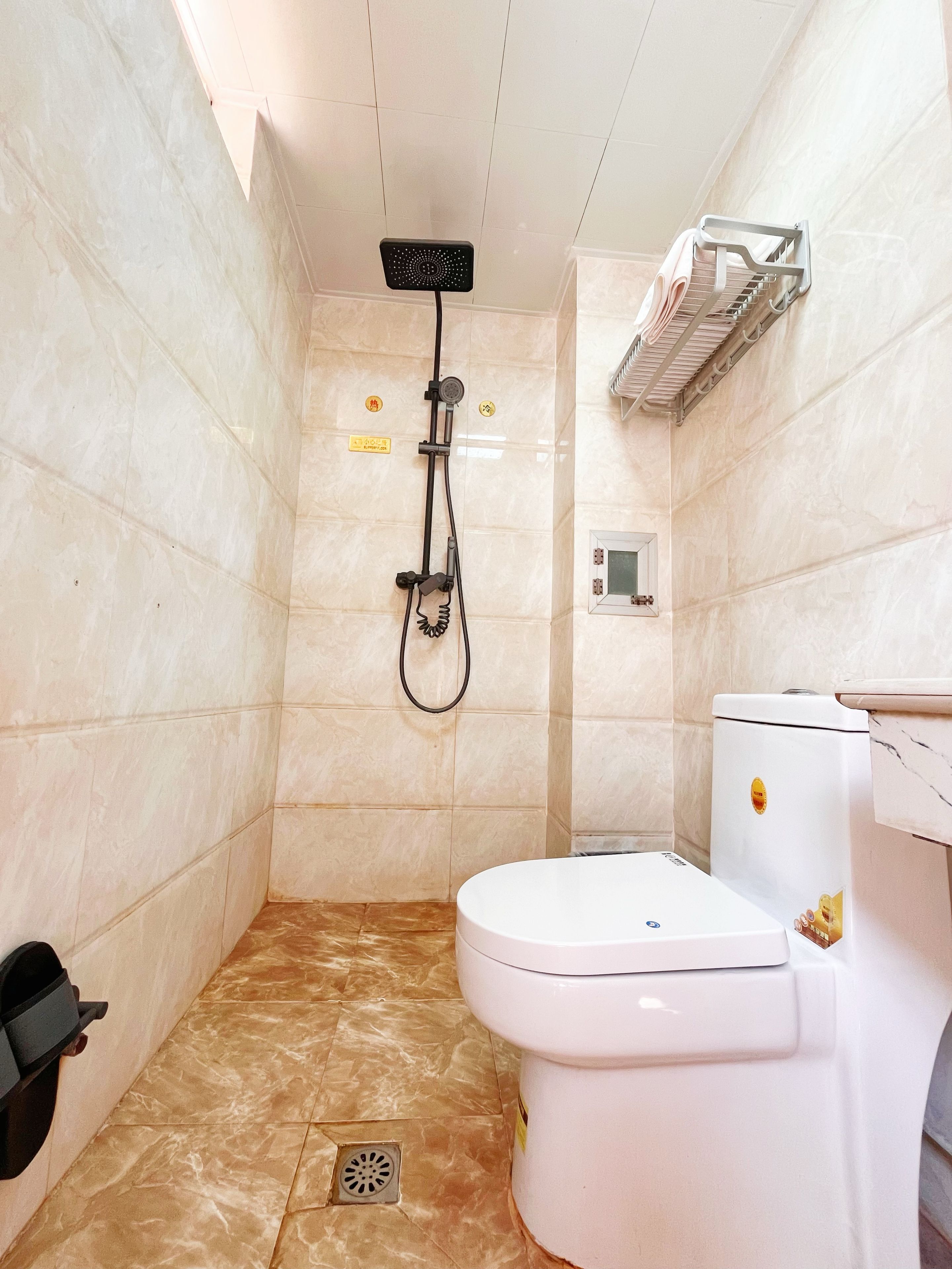 A bathroom with a shower, toilet, and a towel rack.