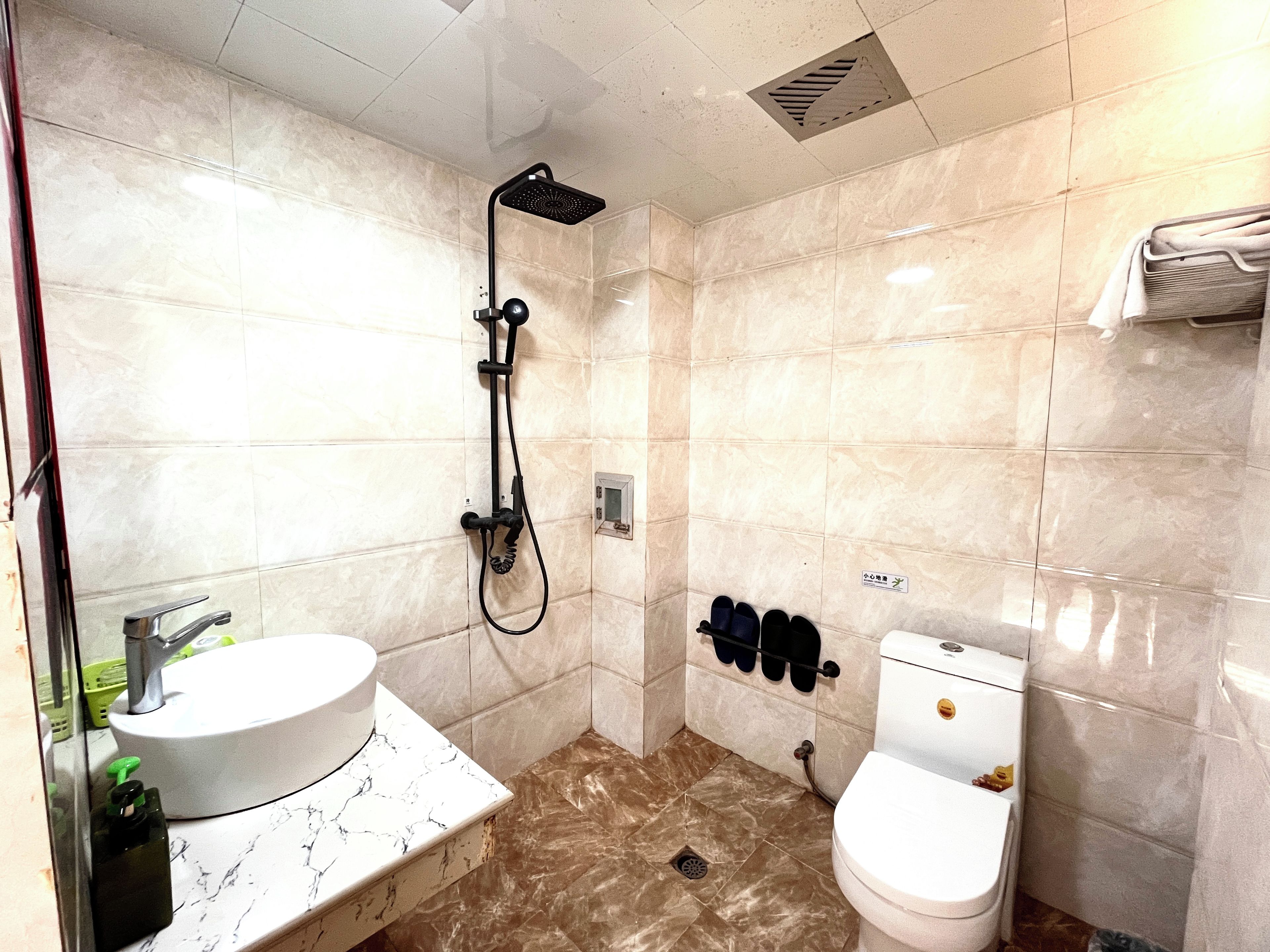 A bathroom with a sink, toilet, shower, and towel rack.
