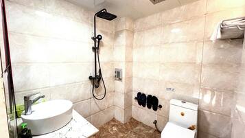 A bathroom with a sink, toilet, shower, and towel rack.
