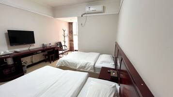 A hotel room with two beds, a desk with a flat-screen TV, a chair, and a wardrobe.
