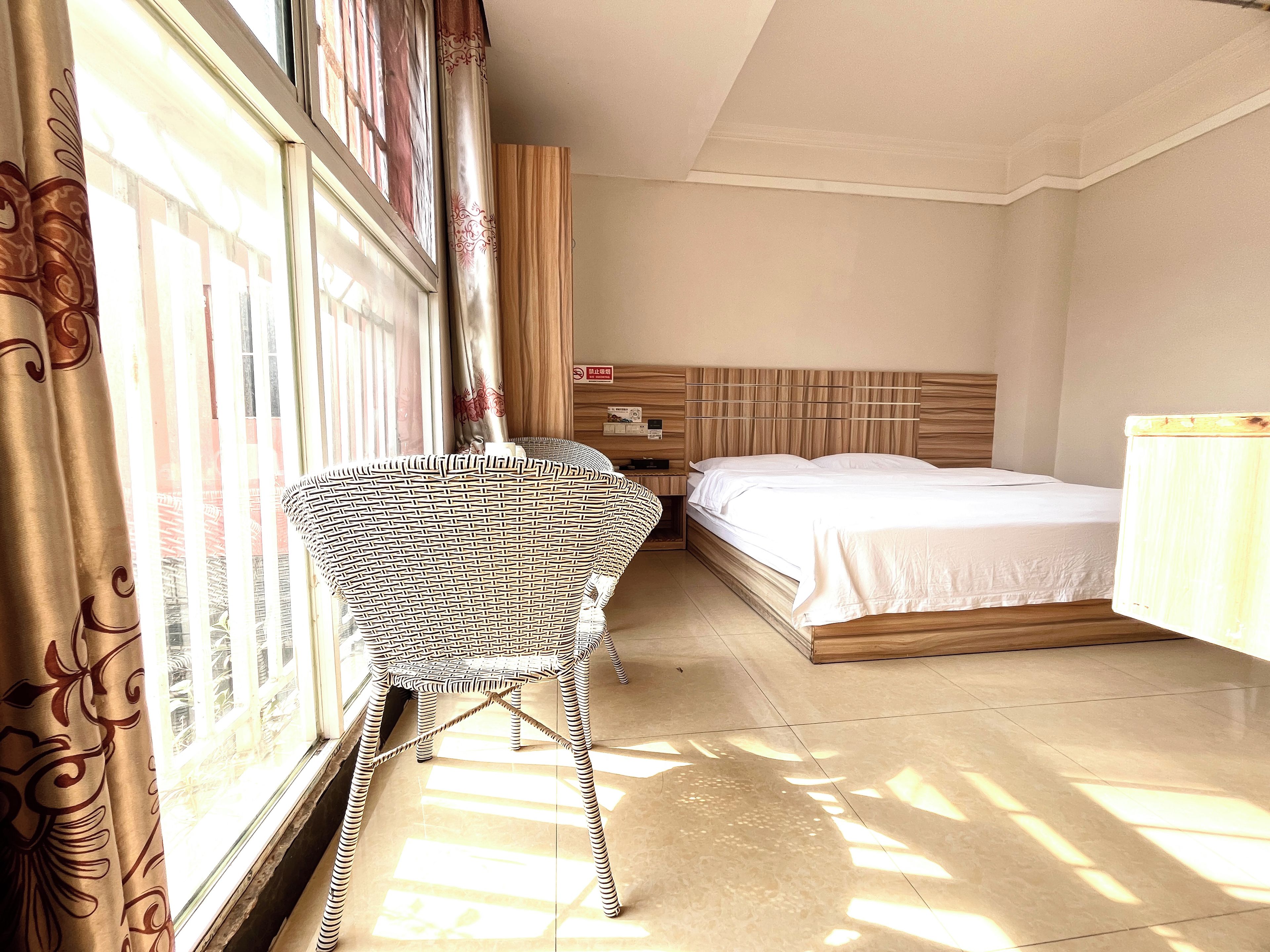 Une chambre d’hôtel avec un lit, une table de chevet, une chaise et une fenêtre avec des rideaux.