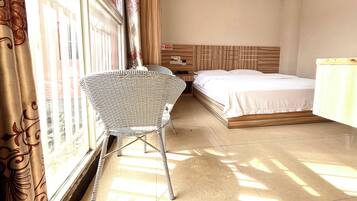 Une chambre d’hôtel avec un lit, une table de chevet, une chaise et une fenêtre avec des rideaux.