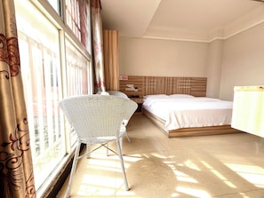 Una habitación de hotel con cama, mesita de noche, una silla y una ventana con cortinas.