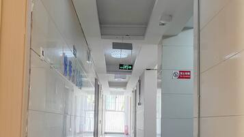 A clean, well-lit hallway with a 'No Smoking' sign, directional signs, and a tiled floor.