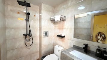 A bathroom with a shower, toilet, sink, and towel rack.