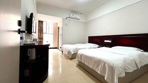 Habitación de hotel con dos camas, un escritorio con silla, un televisor de pantalla plana y un aire acondicionado.