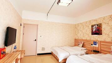 A hotel room with two beds, a desk, a television, and a door.