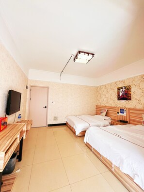 Habitación de hotel con dos camas, un escritorio, un televisor y una puerta.