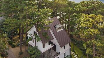 A two-story house with a sloped roof, surrounded by a well-maintained lawn and trees, with a lake in the background.
